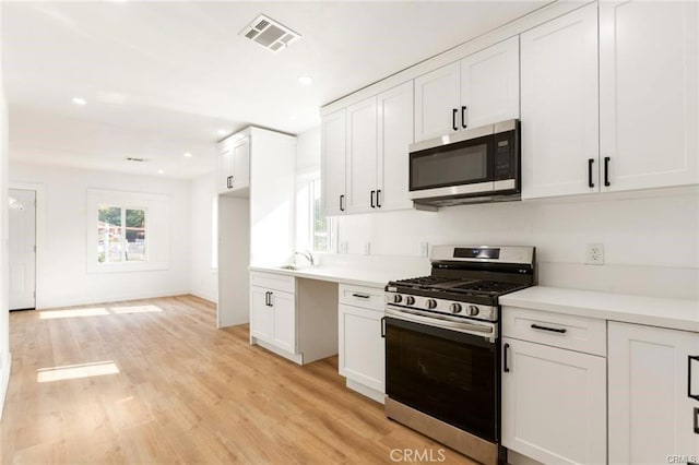 kitchen with white cabinetry, sink, light hardwood / wood-style flooring, and appliances with stainless steel finishes