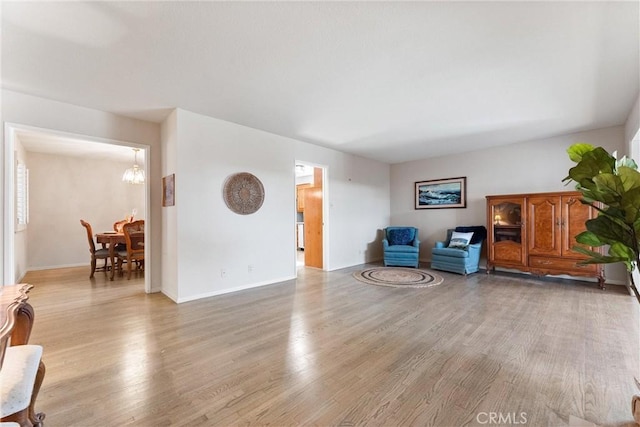 living area with light wood-type flooring and an inviting chandelier