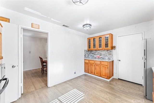 kitchen with stainless steel fridge with ice dispenser, light hardwood / wood-style floors, and tasteful backsplash