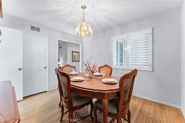 dining room with light hardwood / wood-style floors and a notable chandelier