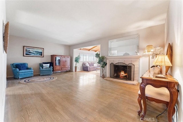 sitting room featuring light wood-type flooring and a brick fireplace