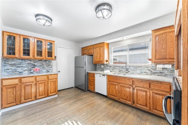 kitchen featuring decorative backsplash, stainless steel fridge, dishwasher, and sink