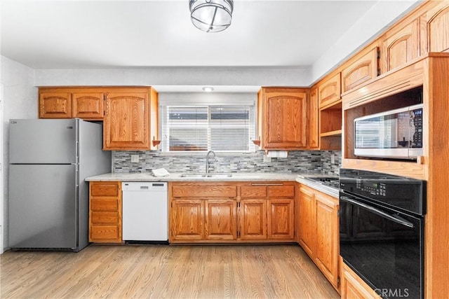 kitchen featuring decorative backsplash, sink, stainless steel appliances, and light wood-type flooring