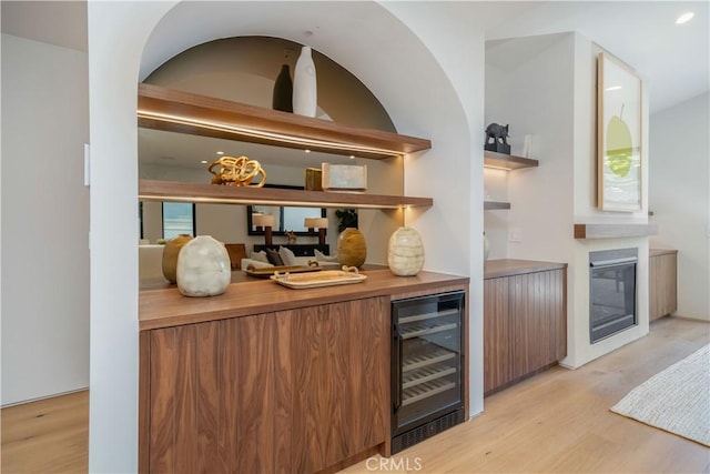 bar with wine cooler and light hardwood / wood-style flooring