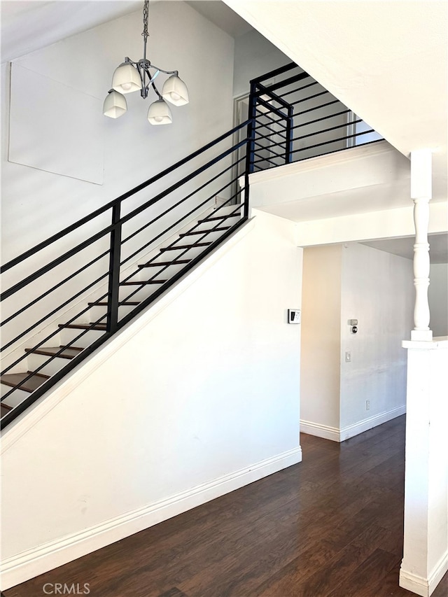 staircase with hardwood / wood-style floors, an inviting chandelier, and a high ceiling