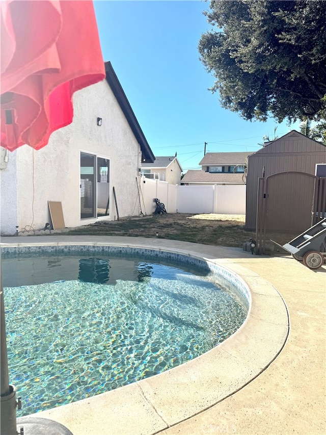 view of swimming pool featuring a storage unit and a patio area