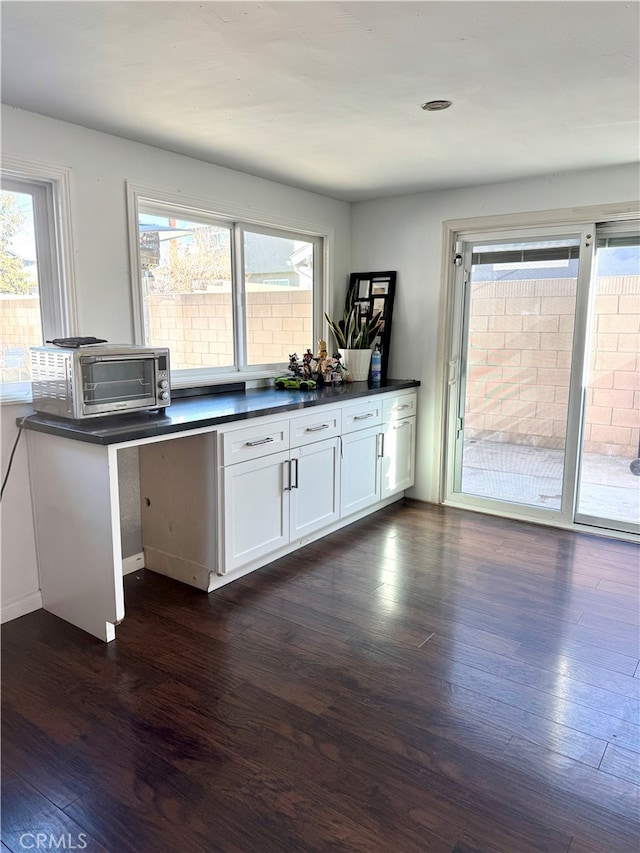 kitchen with kitchen peninsula, white cabinets, and dark wood-type flooring