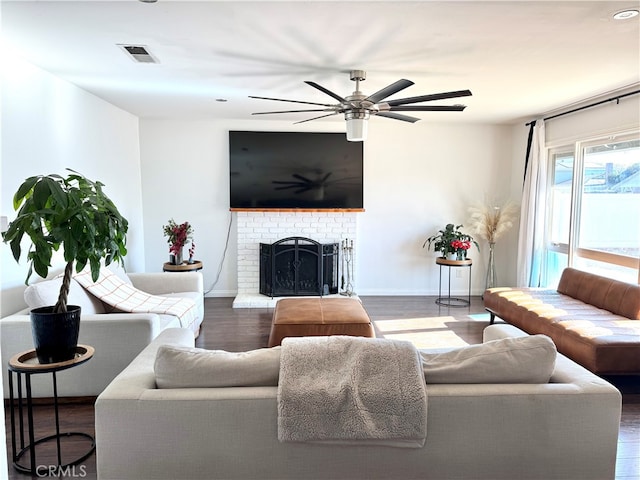 living room featuring ceiling fan, dark hardwood / wood-style floors, and a fireplace