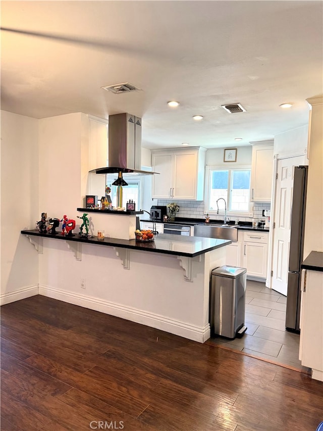 kitchen featuring a kitchen bar, white cabinetry, island exhaust hood, and kitchen peninsula