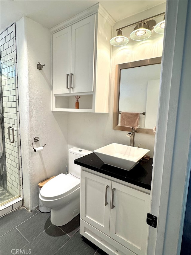 bathroom featuring tile patterned floors, toilet, vanity, and a shower with shower door