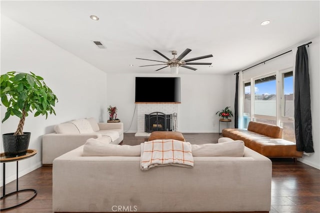 living room with ceiling fan, a brick fireplace, and dark hardwood / wood-style floors