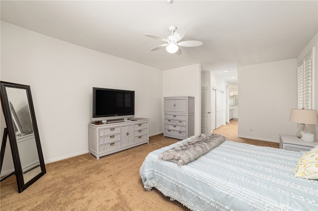 bedroom with ensuite bath, ceiling fan, a closet, and light colored carpet