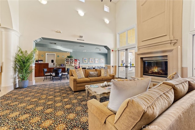 living room with a towering ceiling, carpet floors, and french doors