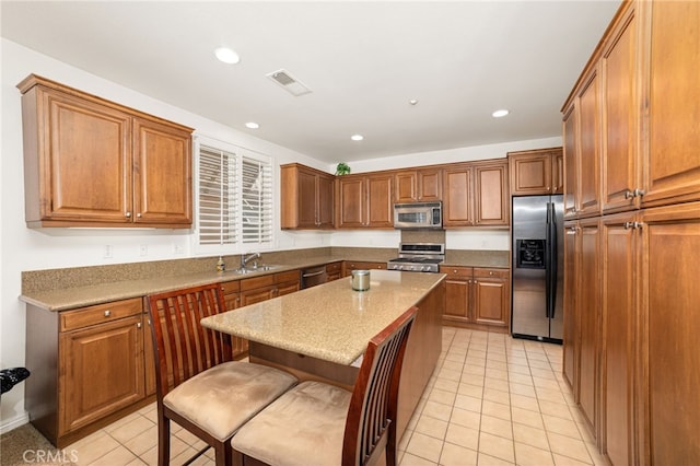 kitchen featuring appliances with stainless steel finishes, a kitchen breakfast bar, sink, a kitchen island, and light tile patterned flooring