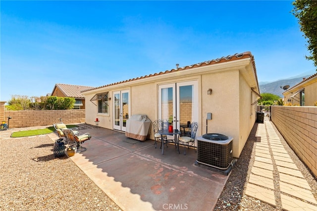 rear view of property with a patio area, a mountain view, and central AC unit