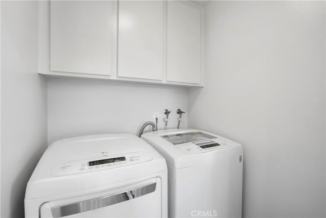 clothes washing area featuring cabinets and washing machine and dryer