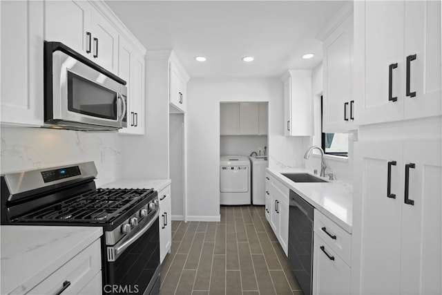 kitchen with separate washer and dryer, stainless steel appliances, white cabinetry, and sink