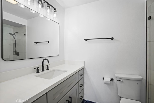 bathroom featuring vanity, toilet, and tiled shower