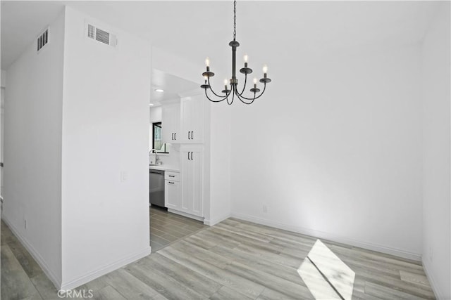 unfurnished dining area with light hardwood / wood-style floors and a chandelier