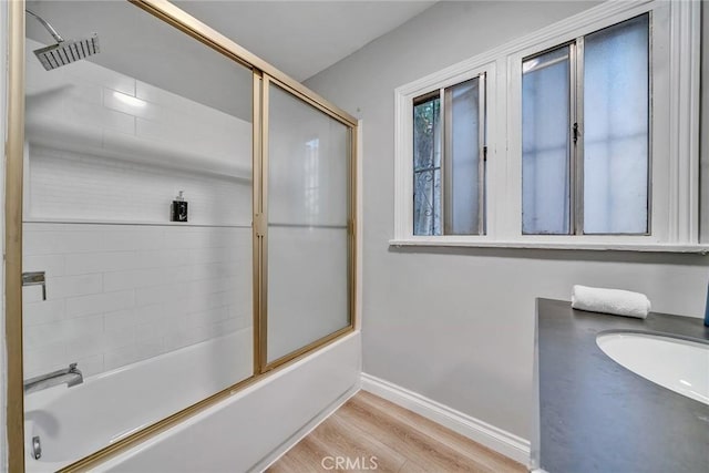 bathroom featuring hardwood / wood-style flooring, vanity, and enclosed tub / shower combo