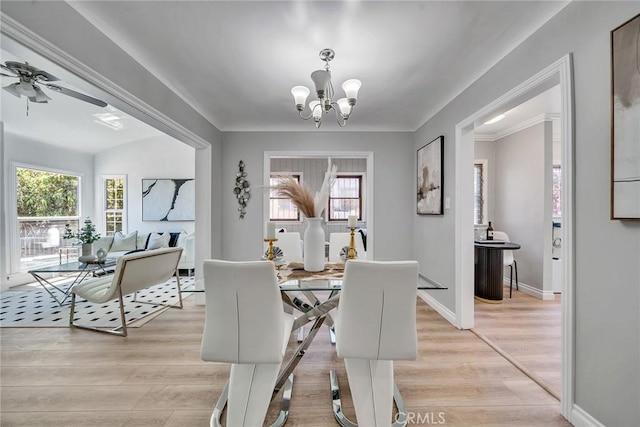 dining room with ceiling fan with notable chandelier, light wood-type flooring, and a wealth of natural light