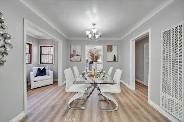 dining space with light hardwood / wood-style floors and an inviting chandelier