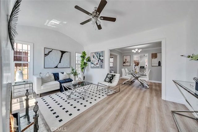 living room featuring plenty of natural light, ceiling fan with notable chandelier, lofted ceiling, and light hardwood / wood-style flooring