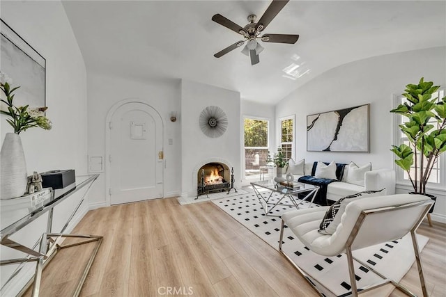 living room with light wood-type flooring, vaulted ceiling, and ceiling fan