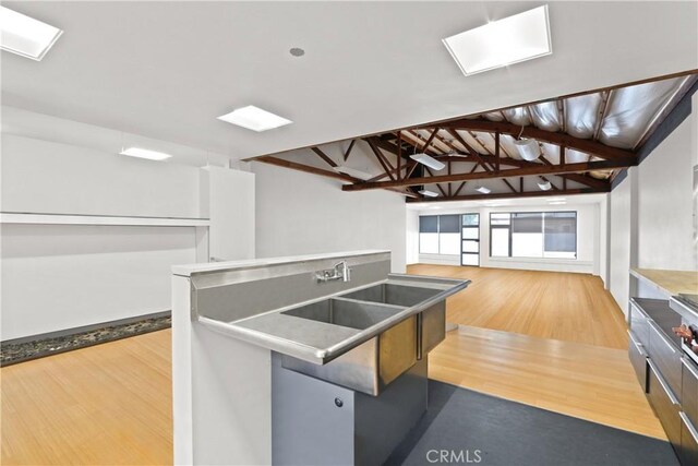 kitchen featuring lofted ceiling, a center island with sink, and light hardwood / wood-style flooring