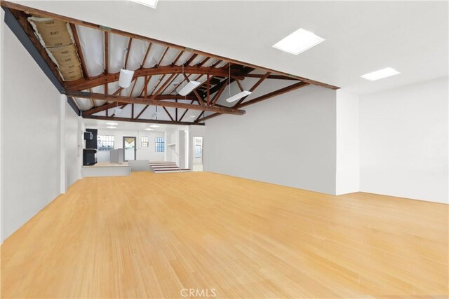 unfurnished living room with high vaulted ceiling, beam ceiling, and hardwood / wood-style floors