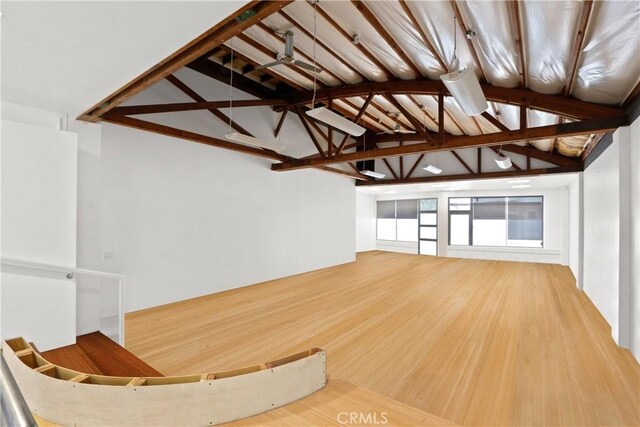 unfurnished living room featuring high vaulted ceiling, hardwood / wood-style floors, and beam ceiling