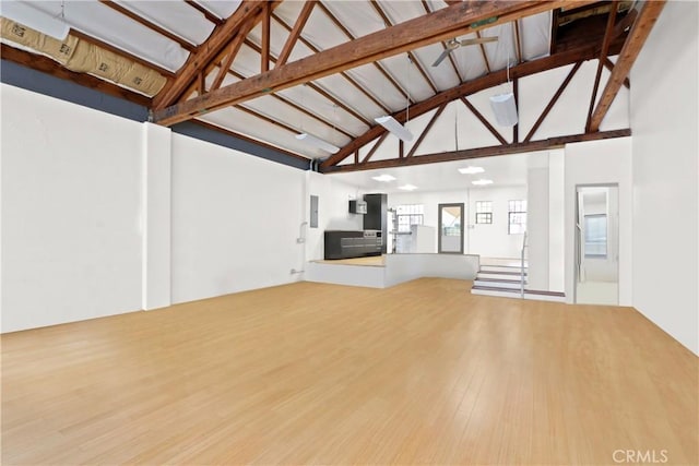 unfurnished living room with high vaulted ceiling, beam ceiling, and wood-type flooring