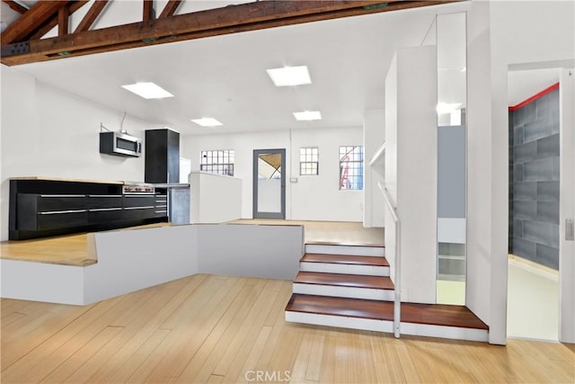 kitchen with light wood-type flooring and lofted ceiling with beams