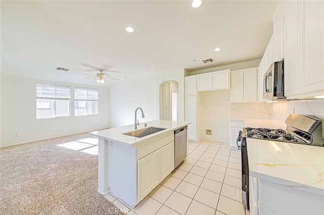 kitchen featuring a center island with sink, white cabinets, appliances with stainless steel finishes, ceiling fan, and sink