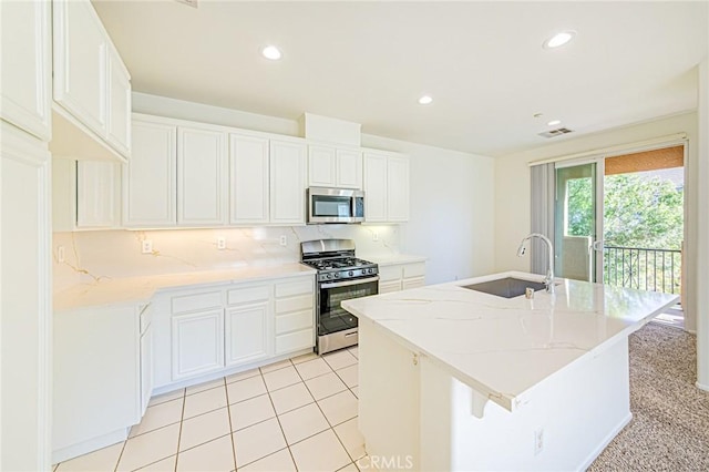 kitchen featuring white cabinets, appliances with stainless steel finishes, a kitchen island with sink, and sink