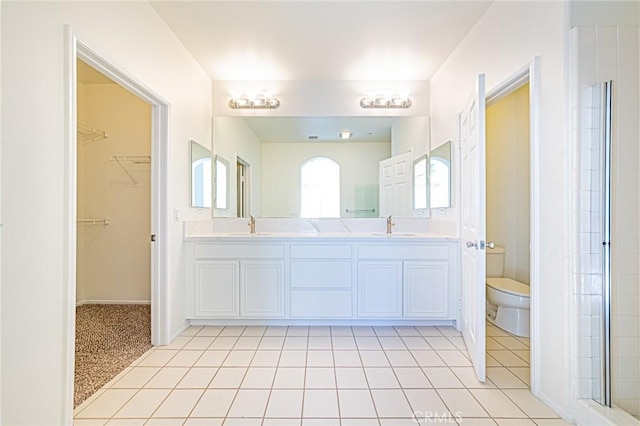 bathroom featuring toilet, tile patterned flooring, a shower with door, and vanity