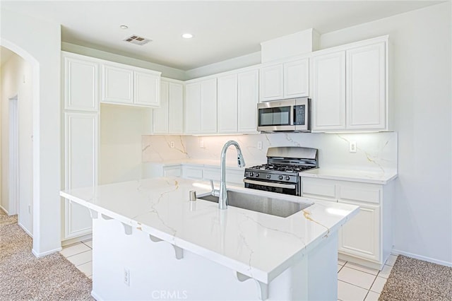 kitchen featuring sink, white cabinetry, a kitchen island with sink, and appliances with stainless steel finishes