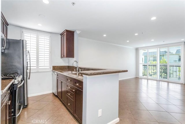 kitchen featuring sink, stainless steel appliances, kitchen peninsula, dark stone counters, and ornamental molding