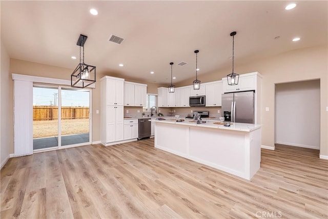 kitchen with white cabinetry, light hardwood / wood-style floors, decorative light fixtures, a kitchen island, and appliances with stainless steel finishes