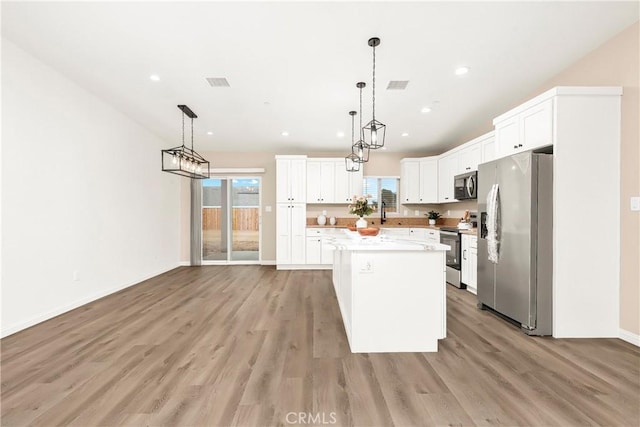 kitchen featuring a center island, light countertops, visible vents, appliances with stainless steel finishes, and light wood-type flooring