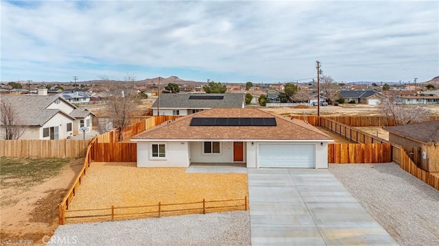 view of front facade featuring a residential view, concrete driveway, a fenced backyard, and roof mounted solar panels