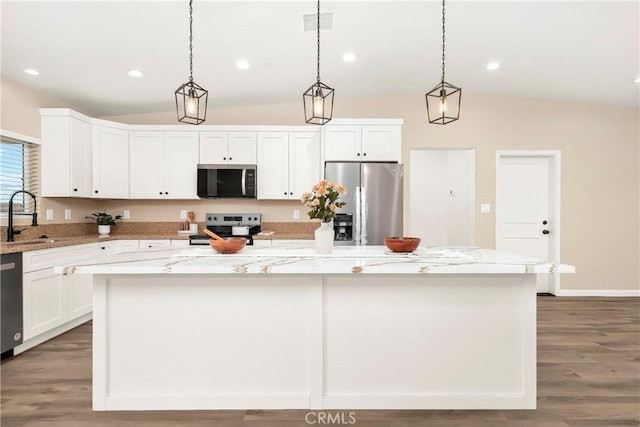 kitchen featuring light stone counters, appliances with stainless steel finishes, white cabinets, vaulted ceiling, and a kitchen island