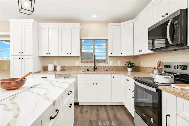 kitchen with appliances with stainless steel finishes, white cabinets, and a sink