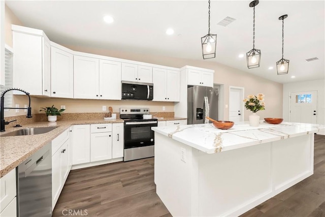 kitchen with appliances with stainless steel finishes, a sink, visible vents, and a center island