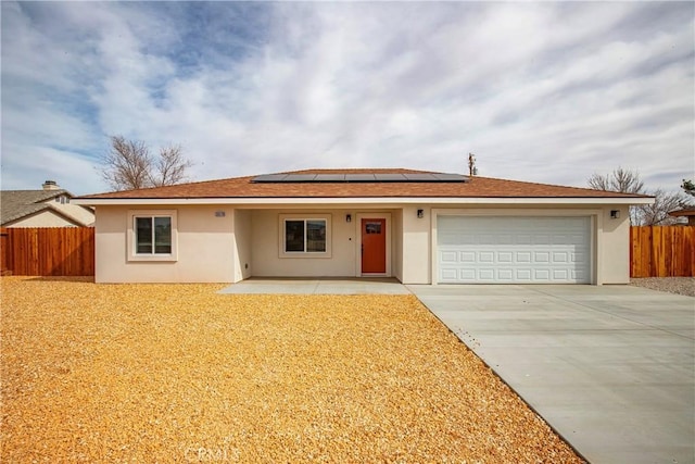 single story home featuring a garage, solar panels, concrete driveway, fence, and stucco siding