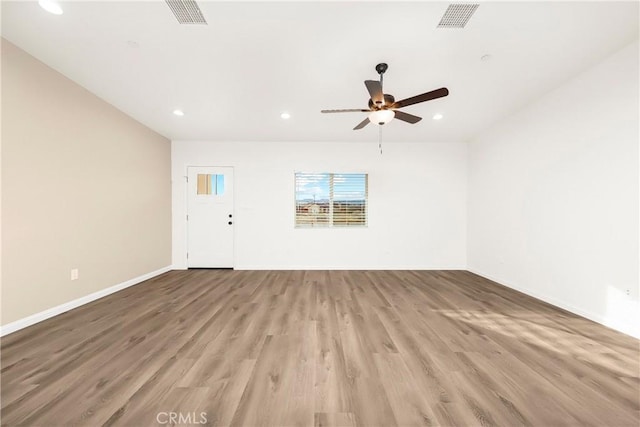 empty room with baseboards, light wood finished floors, visible vents, and recessed lighting