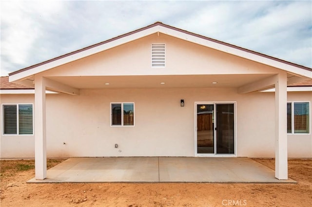 rear view of house with stucco siding and a patio