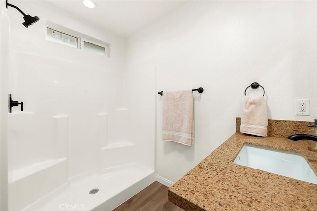 full bathroom featuring walk in shower, a sink, and wood finished floors