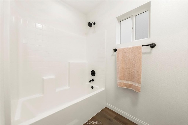 bathroom featuring wood finished floors, shower / tub combination, and baseboards