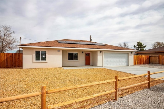 ranch-style home featuring a garage, concrete driveway, fence private yard, and stucco siding